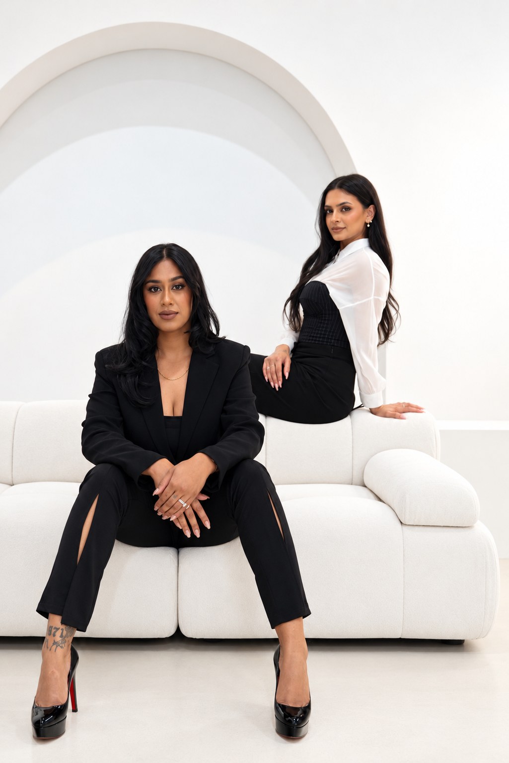 Two founders posed on a white sofa under an arch